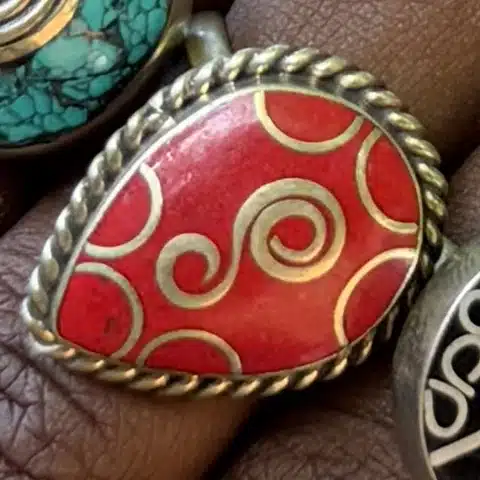Bague artisanale cabochon de corail rouge gravé de spirales dorées, vue de détail