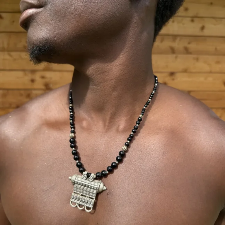 Collier berbère en argent, plaque gravée et perles noires, porté à même la peau
