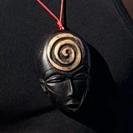 Collier pendentif masque africain en bois noir orné d'une spirale dorée, AKU Creation