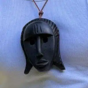 Collier pendentif masque africain en bois noir gravé de stries, porté en sautoir, AKU Creation