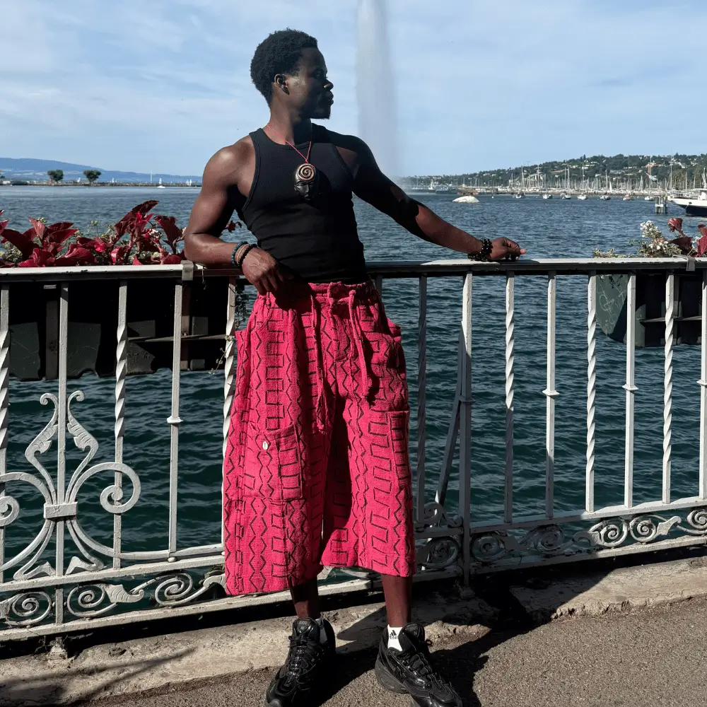 Short baggy en bogolan rose porté par un homme au bord du lac, motifs noirs