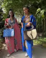 Deux robes Àkua en wax, rose et bleue, portées de face avec sacs artisanaux